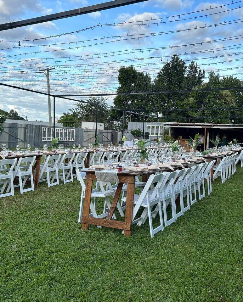 Americana chairs at a wedding around tables on a grass paddock.